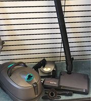 Main vacuum unit on shelf next to floor brush and hose wand