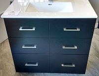 Front view of black vanity cabinet with white ceramic sink top