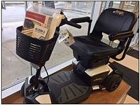 Side-angle view of black and white Pride Jazzy Zero Turn mobility scooter showing padded seat, delta tiller, basket, wheels and foot platform.