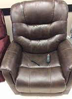 Front view of brown faux leather power lift recliner with remote control on seat