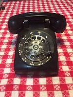 Front view of black rotary dial telephone with labeled dial numbers and letters.