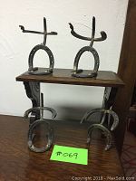 Four metal art figures made from welded horseshoes, displayed on a small table, three figures with bases and one without base.