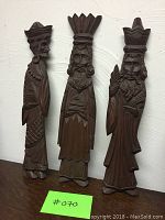 Photo showing the full set of three carved wooden figures representing The Three Kings, standing against a textured wall with a green label marked #070.