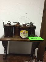 Four brown ceramic Wispride crock jars placed on a wooden surface, each with lids and metal clasps.