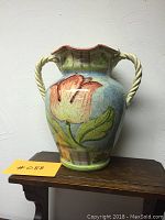 Front view of the large ceramic vase showing the floral design and twisted rope handles.