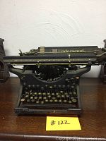 Front view of the vintage Underwood Standard typewriter placed on a wooden surface, showing the keyboard and body structure.