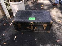 Top down view of vintage black trunk closed, displaying overall size, shape, and condition with visible wear.