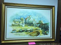 Framed coastal village painting showing boats on the shore with buildings and a bridge in the background by Suzanne Brown.