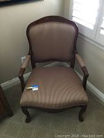 Front view of the upholstered armchair showing wood frame, padded seat and backrest in beige striped fabric.