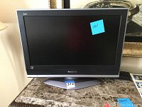 Front view of Panasonic 26 inch TV on countertop with a blue sticky note on screen.