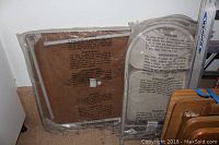 Foldable card table and chairs wrapped in protective plastic against a wall