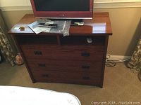 Front view showing three drawers, open shelf on top with items placed, dark wood finish.