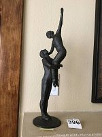 Front-left angle view of the ballet couple statue showing the male figure lifting the female figure high with her right arm extended upward.