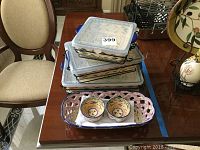 Photo showing four stacked rectangular ceramic serving trays with lids and black metal stands.