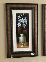 Full view of floral wall art in ornate dark brown and black frame with double matting.