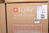 Close-up of cardboard packaging labeled IQAir Air Purification System High-Performance Swiss Made with lot sticker 421