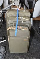 Three olive green Briggs & Riley suitcases stacked together with exercise equipment in background