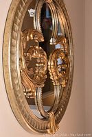 Side angle showing ornate carved gold frame with scrollwork and beaded detailing.