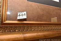 Close-up of bottom edge of wood frame showing carved leaf detail and chip damage.