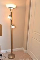 Full view of the entire floor lamp showing the pole, base, and the three lights with their white frosted shades.