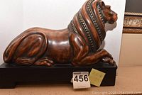 Side profile of the reclining lion statue showing its overall shape and size on a black pedestal.