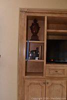 Image showing a wooden shelving unit with a decorative urn on the upper shelf and the black and silver box with leopard figurine on the lower shelf.