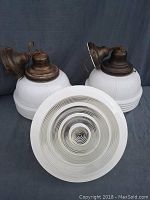 Three pendant fixtures displayed together showing white glass shades and metal canopies