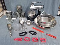 Lot arranged on table showing canisters, bowls, glass shakers, cookie cutters, and mixer.
