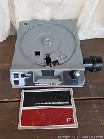 Full view of Kodak Ektagraphic II E projector with manual placed below it showcasing the front and top carousel design.