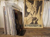 Comic books stacked vertically alongside an Andromeda Collector's Edition poster showing winged characters.
