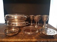 Full view of all items showing three goblets, two round trivets, an oval dish, and a small handled dish