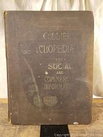 Front cover showing the title 'Collier's Cyclopedia of Social and Commercial Information' in gold lettering on a dark cloth cover, worn with age and some damage.