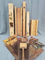 Front view of the collection showing four hand saws with wooden handles, a wooden mallet, and four wooden planes lined up behind them.
