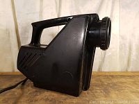 Side view of the black Magnajector projector showing carrying handle and vent slits