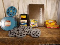 Full lot overview showing multiple blue and grey film reels, Kodak film rolls in boxes, Castle Films box, and movie album binder