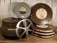 Overall stack of silver and brown metal film cans with one loose reel in front