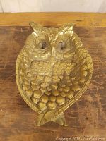 Front view of the brass owl ashtray highlighting detailed feather and eye design.