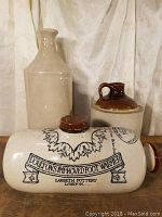 Grouped shot showing Doulton's Improved Foot Warmer with three jugs behind, cream and brown colors.