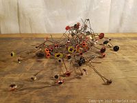 Glass eyes attached to thin wire stems in assorted colors and sizes spread out on a wooden surface.