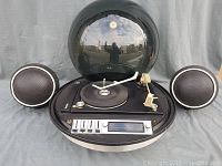Front view of console with bubble top open and two spherical speakers