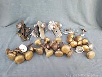Photo of assorted vintage door knobs including metal and glass pieces with backplates and hardware on grey backdrop.