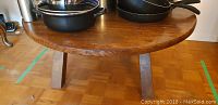 Round sturdy wooden table shown from side angle, highlighting thick legs and tabletop surface.