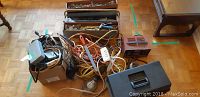 Photo showing vintage toolbox closed with extension cords and battery charger, cords tangled together.