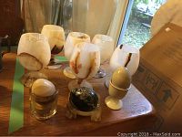 Six alabaster goblets in cream and brown patterns, one with base chip, alongside an ashtray and three decorative eggs