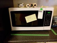 Front view of Hamilton Beach microwave oven with a note taped on the door and a lot sticker on top left corner.