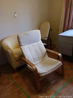 Group of three chairs: IKEA Poang armchair in front, yellow armchair in back left, wooden rocking chair in back right.
