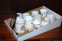 Assorted mugs, pins and compact mirror in cardboard tray