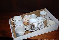 Eight Royal Family commemorative mugs arranged in tray showing varied designs and styles