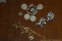 Photo showing bracelet with dimes and several metal pins including star and leaf shapes.