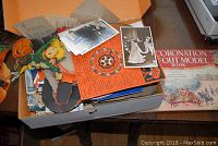 Top view of an open box containing vintage Halloween decorations, various postcards, tobacco cards, and other vintage paper items.